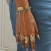 A Golden Hollow Patterned Bracelet Ring with Blue Faux Turquoise Tassels And Hollow Metal Designs, Embodying a Bohemian Vacation Style.
