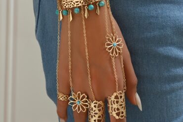 A Golden Hollow Patterned Bracelet Ring with Blue Faux Turquoise Tassels And Hollow Metal Designs, Embodying a Bohemian Vacation Style.